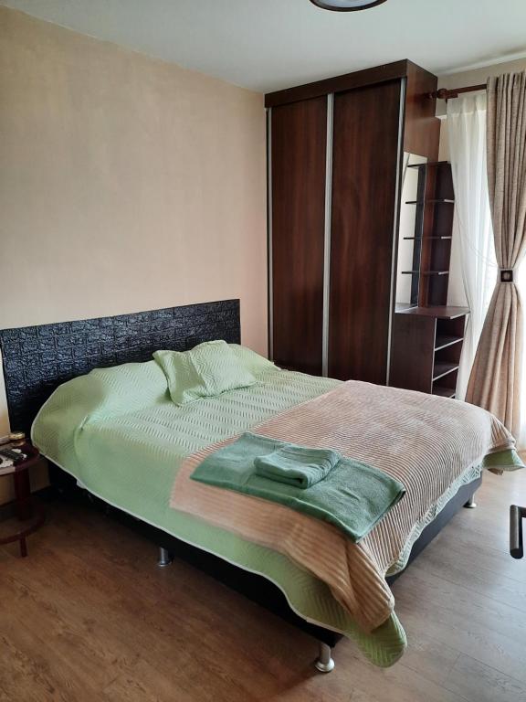 a bedroom with a bed with a green blanket on it at Experiencia Recoleta in Cochabamba