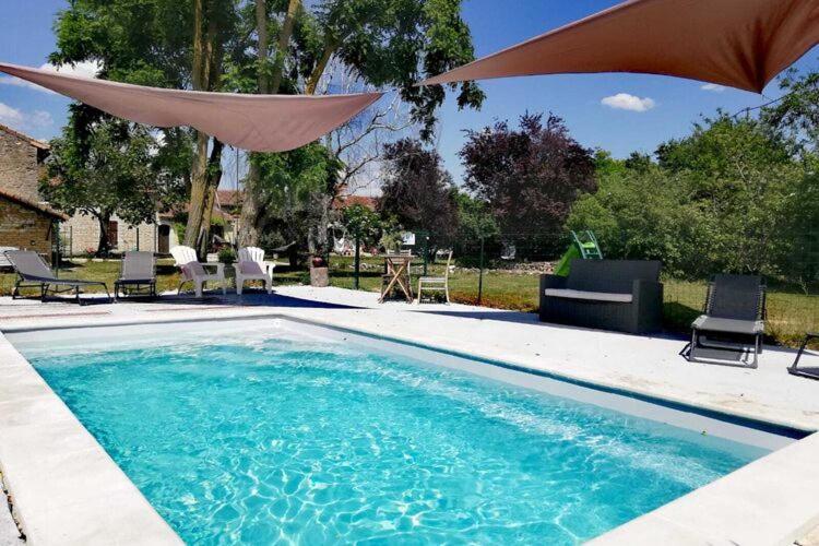 uma piscina com guarda-sol, cadeiras e mesas em Spacious cottage with terrace em Frontenay-sur-Dive