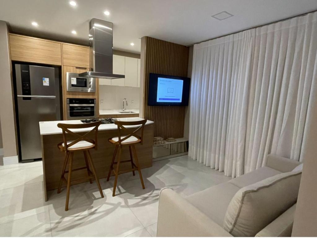 een keuken met een bar met krukken en een bank bij Novinho em Camboriú in Balneário Camboriú