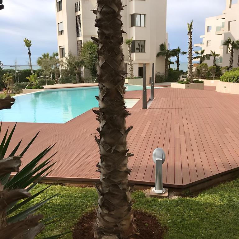 a palm tree in a yard next to a swimming pool at Apparemment Rockisland in Mohammedia