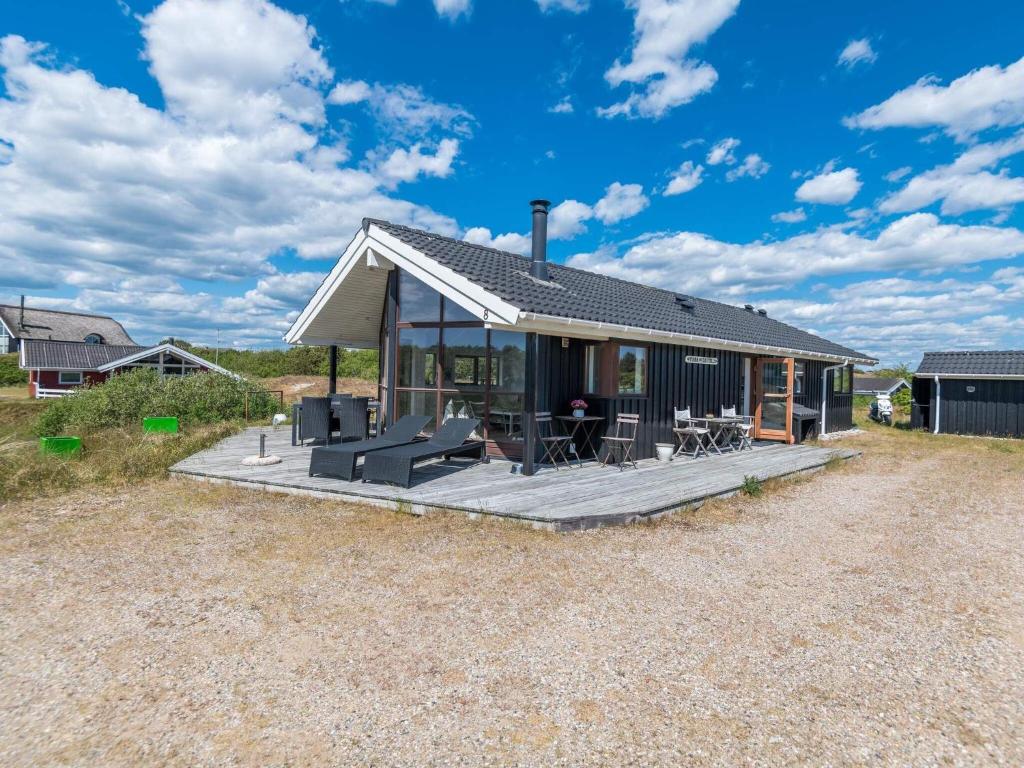 a small house with a wooden deck in a field at Holiday home Fanø VII in Fanø