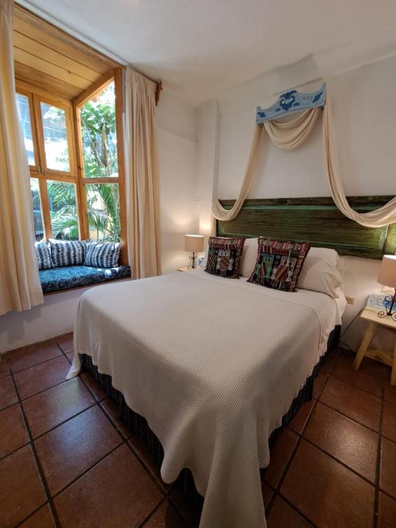 a bedroom with a large bed and windows at Yellow House Hostel B&B in Antigua Guatemala