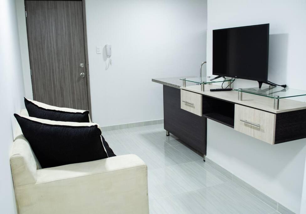 - un salon avec une télévision et un canapé dans l'établissement Apartahotel 222 Apartamento 304, à Pereira