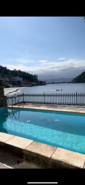 a large swimming pool next to a body of water at Hostel Parque Prainha in São Vicente