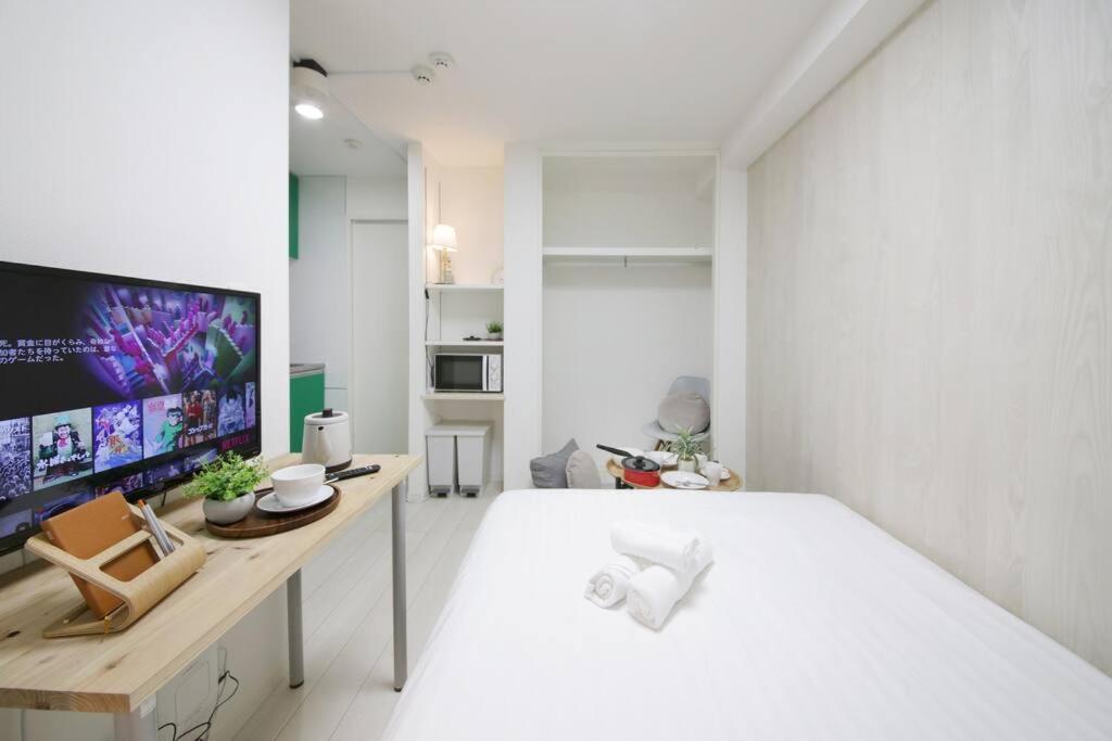 een witte slaapkamer met een groot bed en een bureau bij Real Kinshi 201 in Tokyo