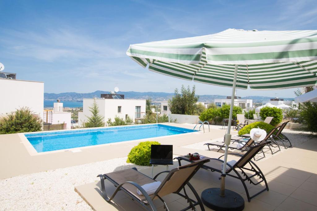 un patio con mesa, sombrilla y piscina en Esprit Villa 26 Latchi en Polis Chrysochous