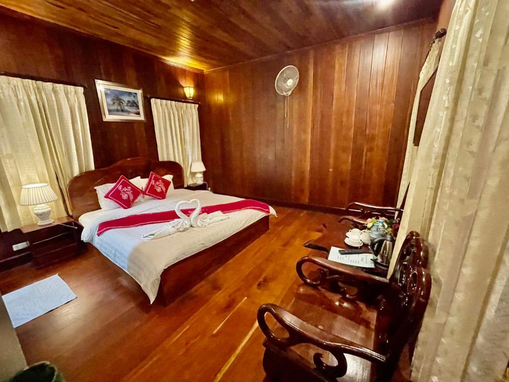 a bedroom with a bed and wooden walls and wooden floors at Villa Phathana Boutique Hotel in Luang Prabang