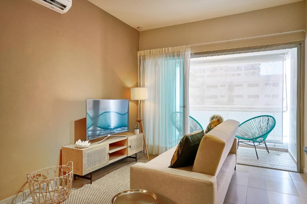 een woonkamer met een bank, een tv en een raam bij Apartamento con piscina y parqueo, encanto urbano in Ciudad Nueva