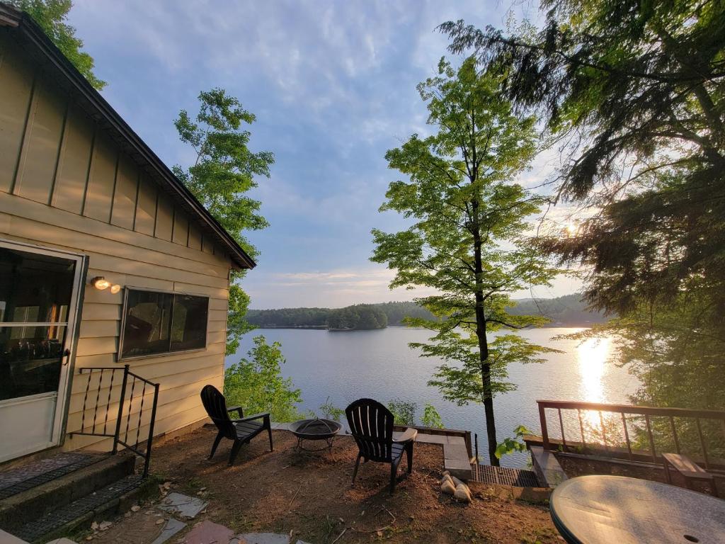 a house with chairs and a view of a lake at Camp Lake Bear in South Colton