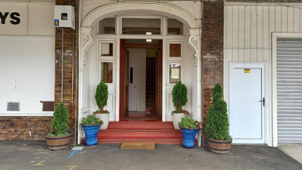 une porte d'entrée d'un bâtiment avec des plantes en pot dans l'établissement Royal Accommodation, à Stratford