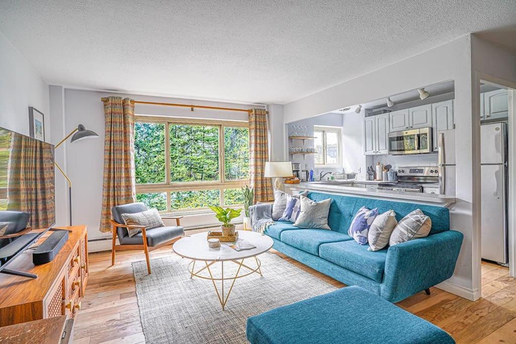 a living room with a blue couch and a kitchen at Tranquil 2BR downtown condo, Parking, King bed in Seattle
