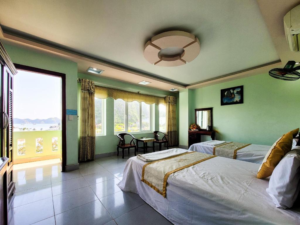 a bedroom with two beds and a table and a ceiling fan at Nhật Anh Hotel Cát Bà in Cat Ba