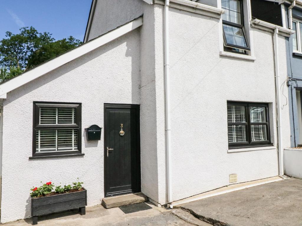a white house with a black door and a window at 3 Bridge Villas in Narberth