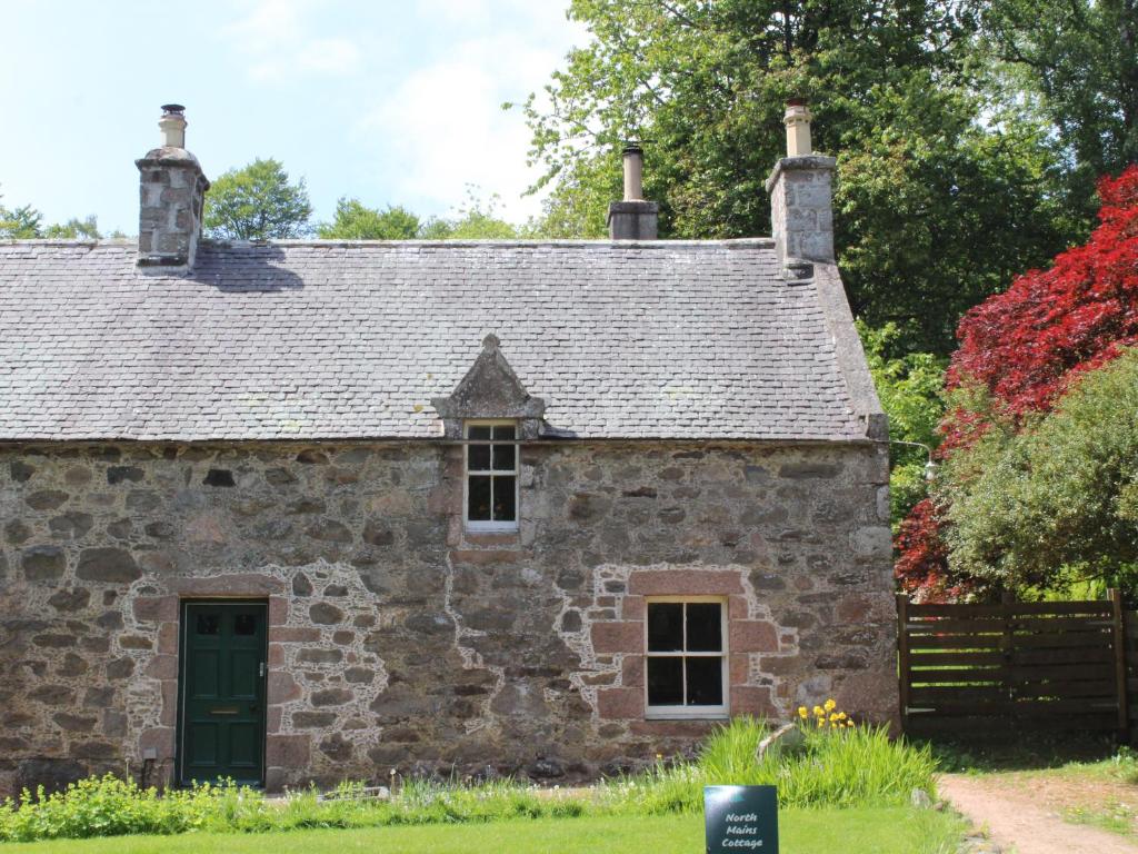 uma antiga casa de pedra com uma porta verde em North Mains Cottage - Craigievar Castle em Alford