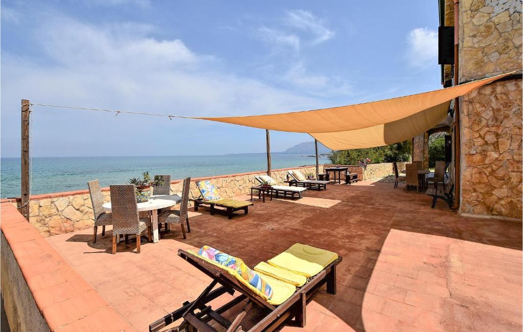 d'une terrasse avec des chaises et des tables donnant sur l'océan en arrière-plan. dans l'établissement Awesome Home In Trappeto With Wifi, à Trappeto