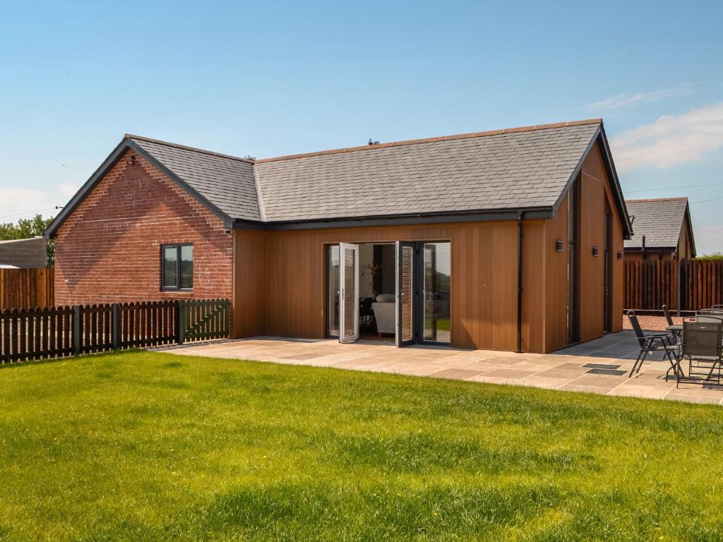 uma casa de estilo celeiro com um pátio e relva em Fell View Cottage - Uk43378 em Kirklinton