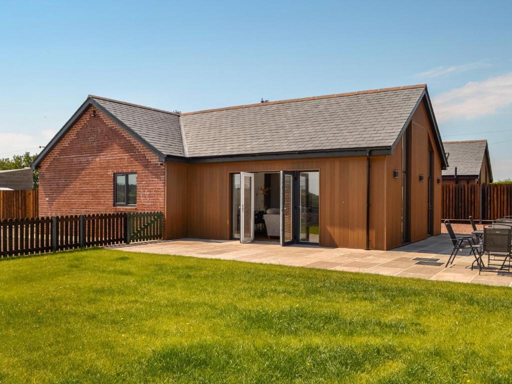 a barn style house with a patio and grass at Fell View Cottage - Uk43378 in Kirklinton
