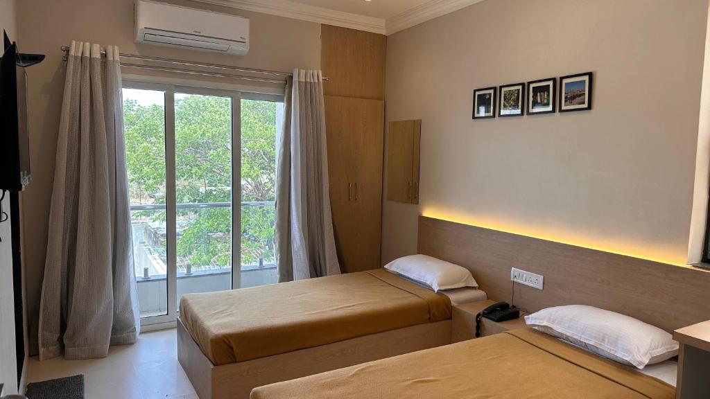 a hotel room with two beds and a window at Hotel Unnati in Aurangabad