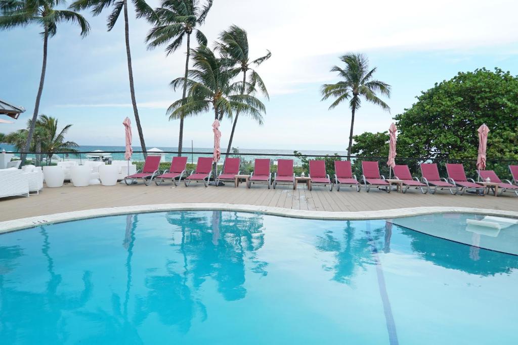 une piscine avec des chaises et l'océan en arrière-plan dans l'établissement Deluxe Apartments by South Florida Vacations, à Miami Beach