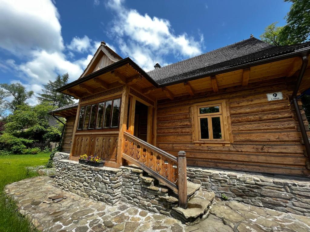 une cabane en rondins avec une terrasse couverte et une passerelle en pierre dans l'établissement Organistówka, à Rabka-Zdrój