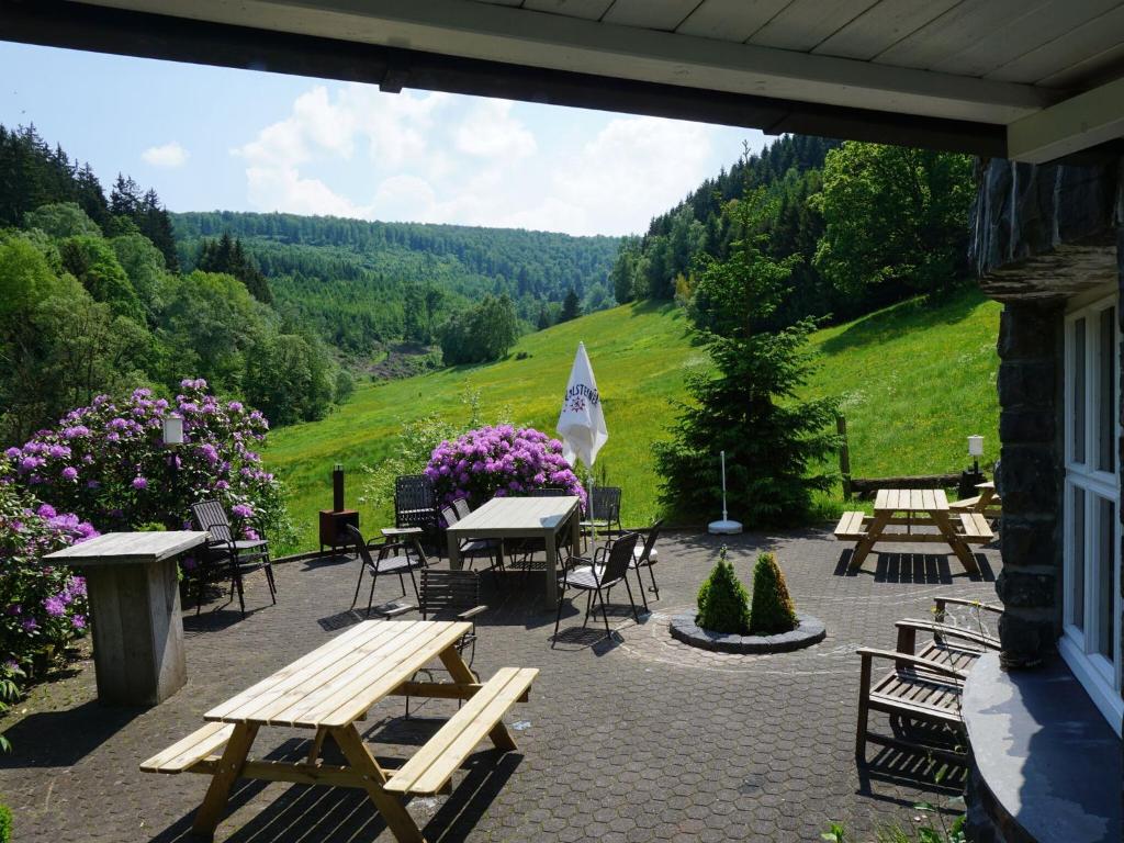 a patio with picnic tables and chairs and flowers at Exclusive group house in Winterberg in the forest in Winterberg