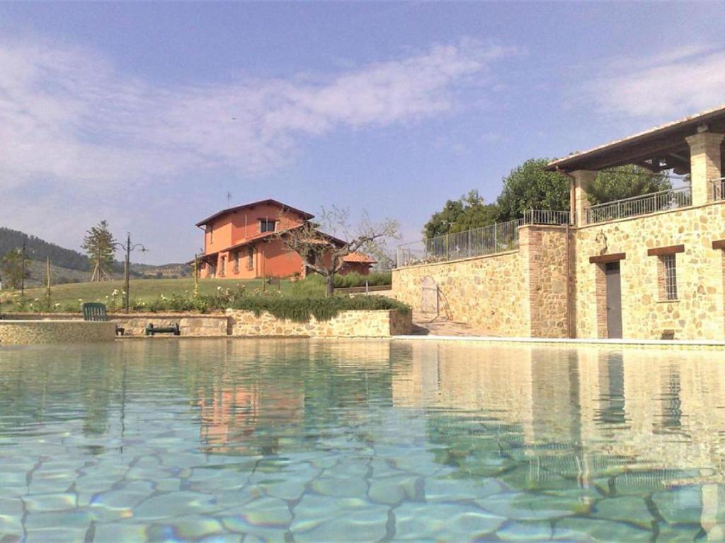 a large pool of water in front of a house at Holiday apartment on a farm in Umbria in Bettona