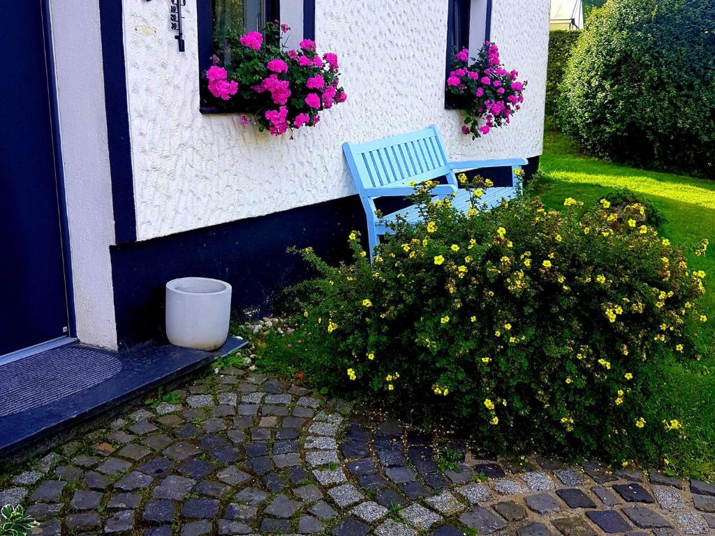 um banco azul sentado fora de uma casa com flores em Apartment with garden in a wooded setting em Auw