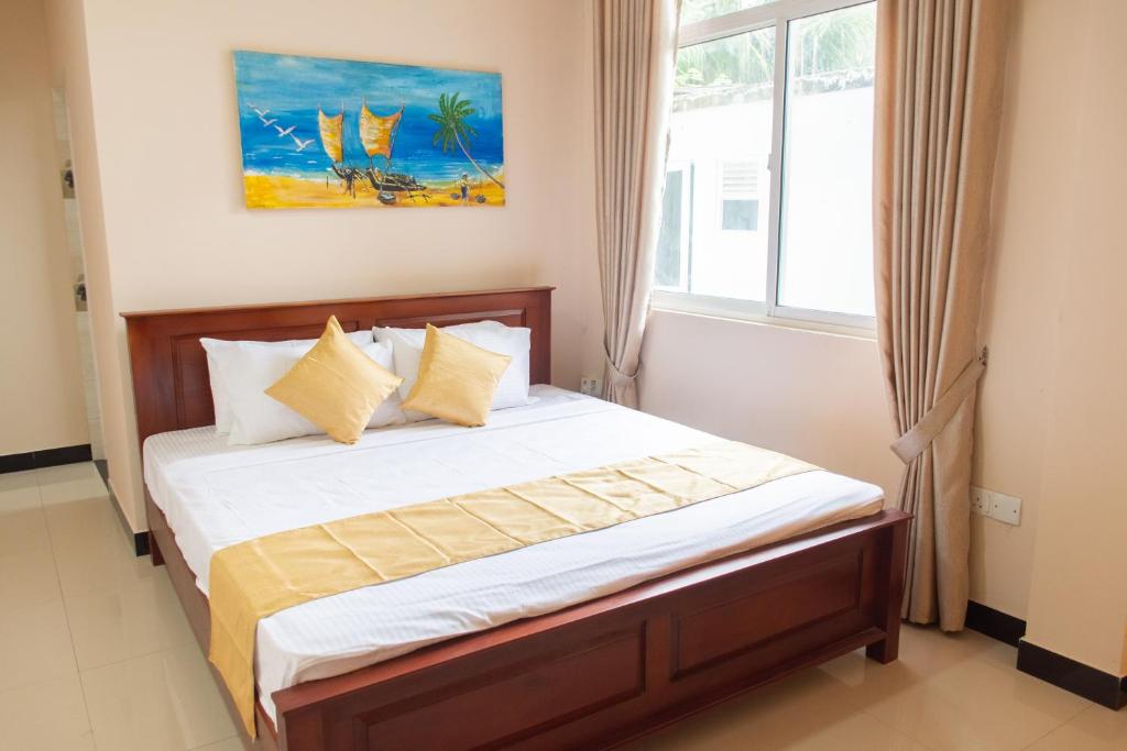a bedroom with a bed with white sheets and a window at Transit Trails in Katunayake