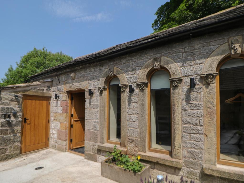 a stone building with wooden doors and windows at Woodbine Retreat in Buxton