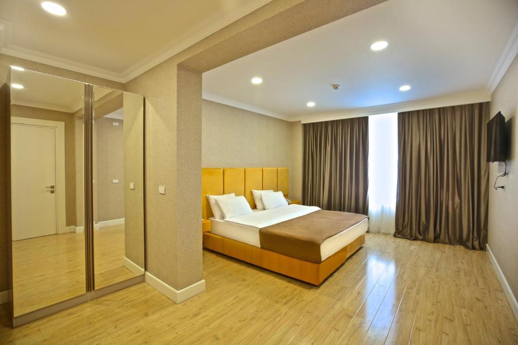 a bedroom with a bed and a large window at Rusel Park Hotel in Baku