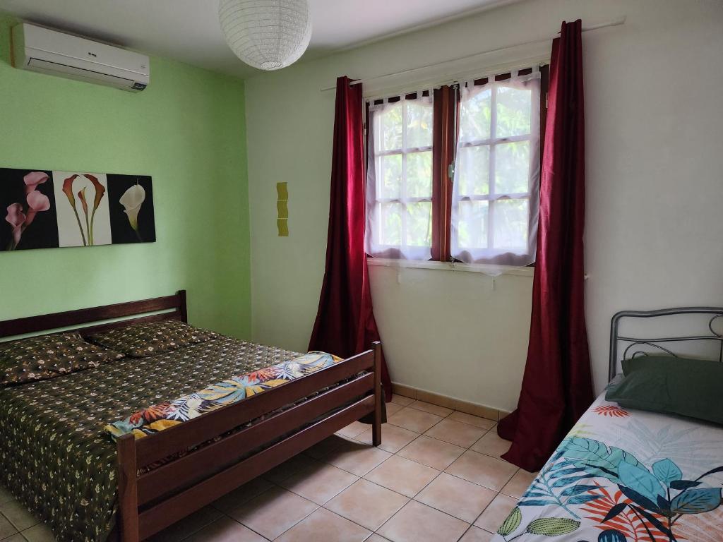 - une chambre avec un lit et une fenêtre avec des rideaux rouges dans l'établissement Villa PANAM' chez R'Marine439 locations saisonnières, à Sainte-Rose