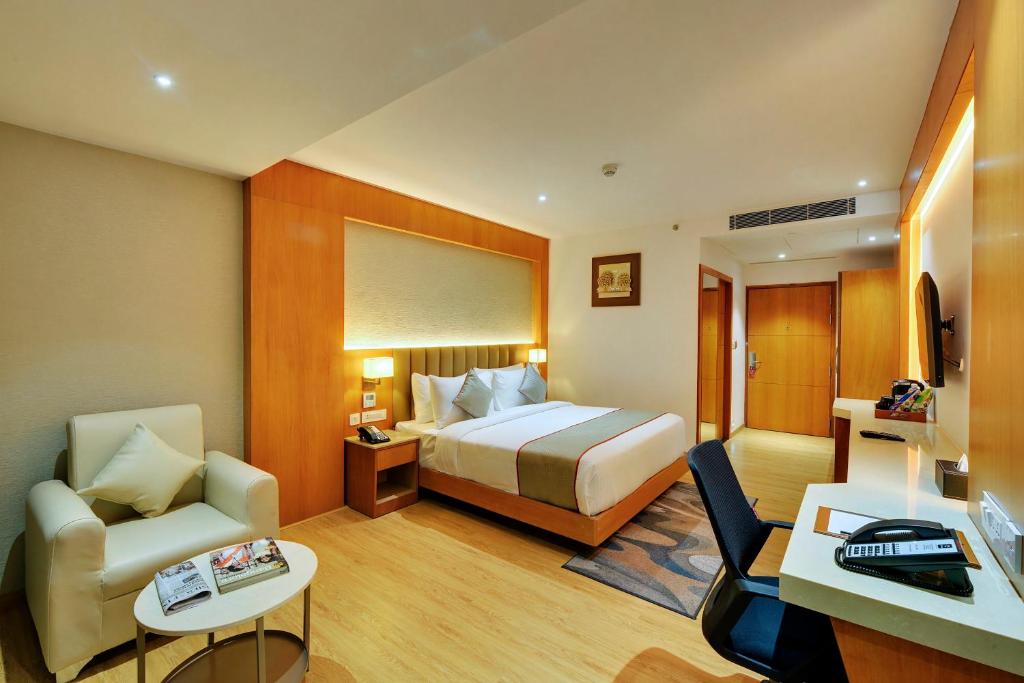 Pokój hotelowy z łóżkiem i krzesłem w obiekcie Clarion Hotel Bangalore w mieście Bengaluru