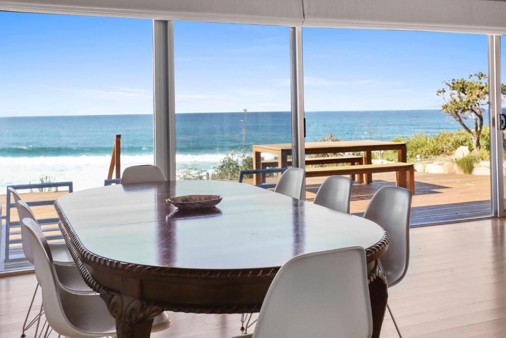 a dining room with a table and chairs and the ocean at The Breakers - Bunga Street 49 in Bermagui