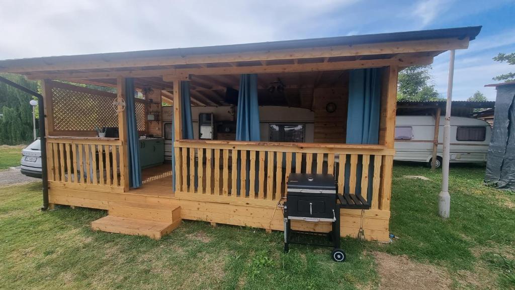 een groot houten huis met een grill in een tuin bij Каравана Тиана in Sozopol