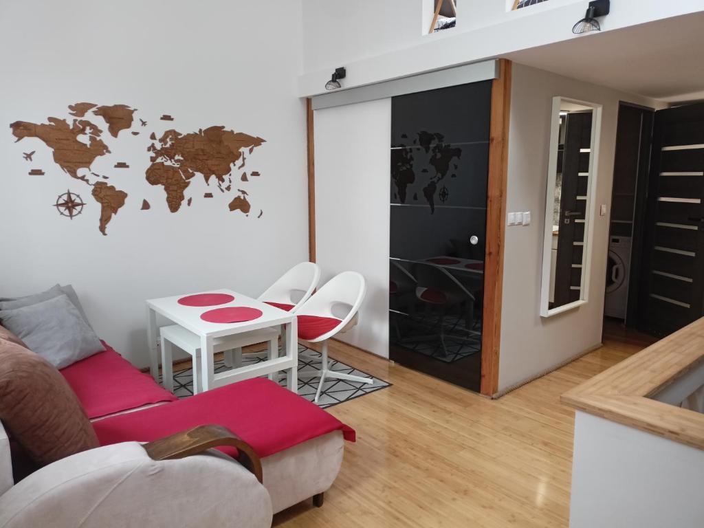 a living room with a table and a world map on the wall at Apartament z antresolą in Darłowo