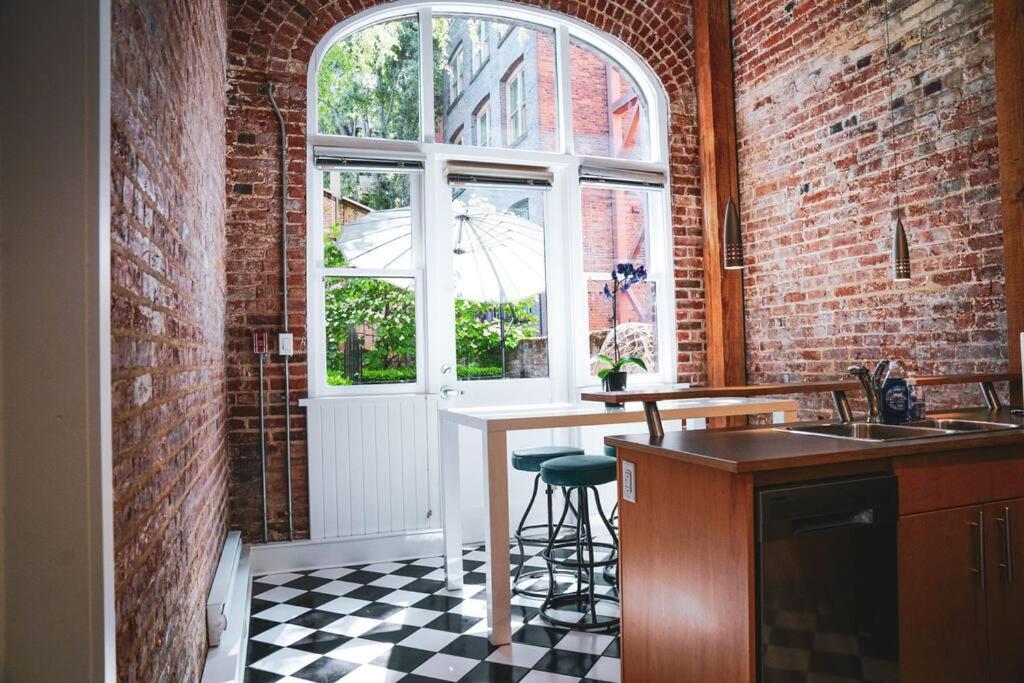 a kitchen with a counter and a window in a brick wall at Historic Charm in Victoria BC's Waddington Alley in Victoria