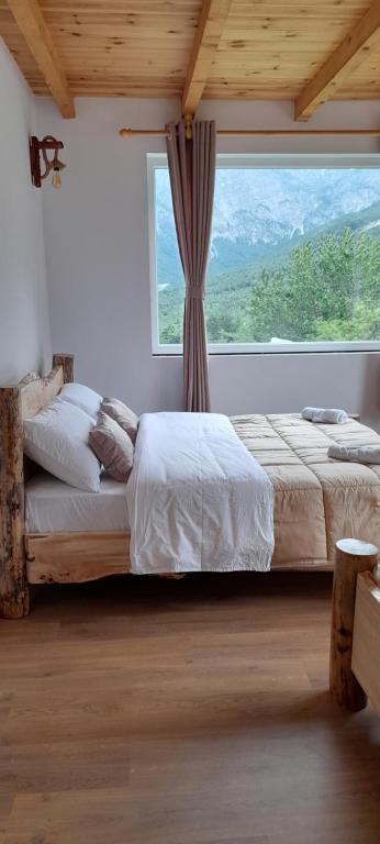 a bedroom with two beds and a large window at Guesthouse Dritan Tethorja in Theth