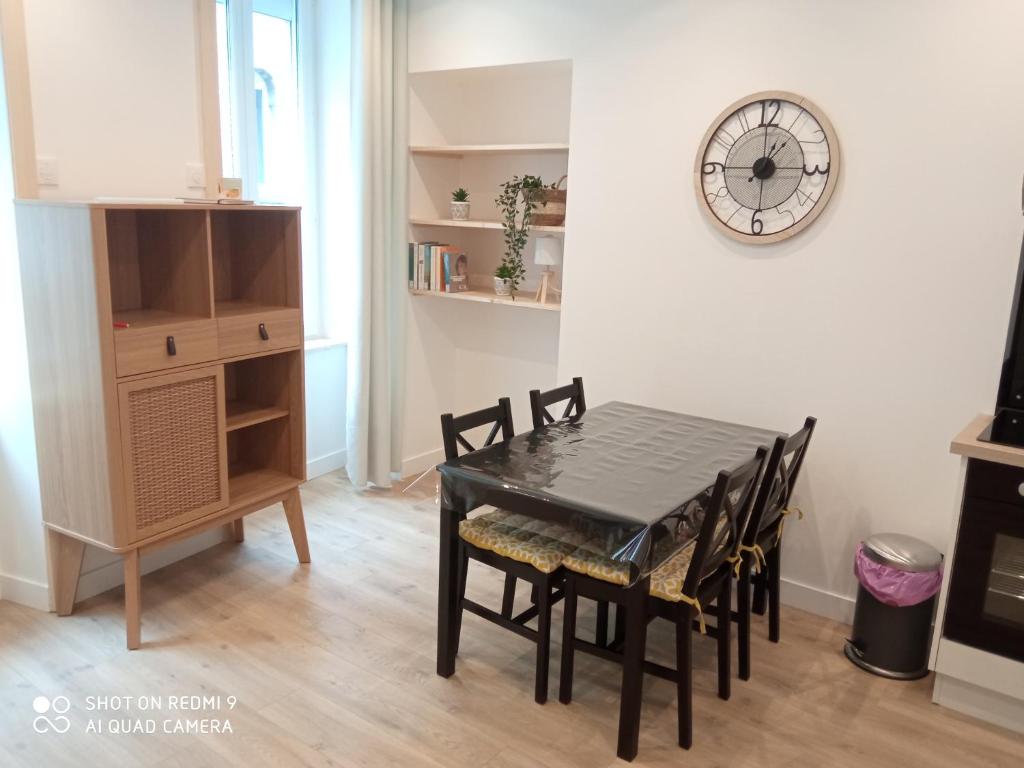 a dining room table with chairs and a clock on the wall at Appartement RDC in Cherbourg en Cotentin