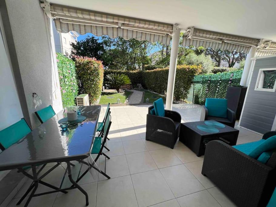 a living room with a table and chairs and a patio at Magnifique 2 pièces, jardin et parking in Saint-Laurent-du-Var