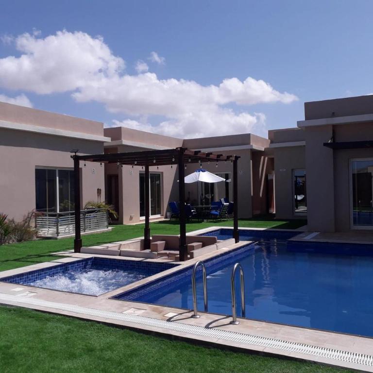 a villa with a swimming pool in front of a house at Blue Revan chalet in Salalah
