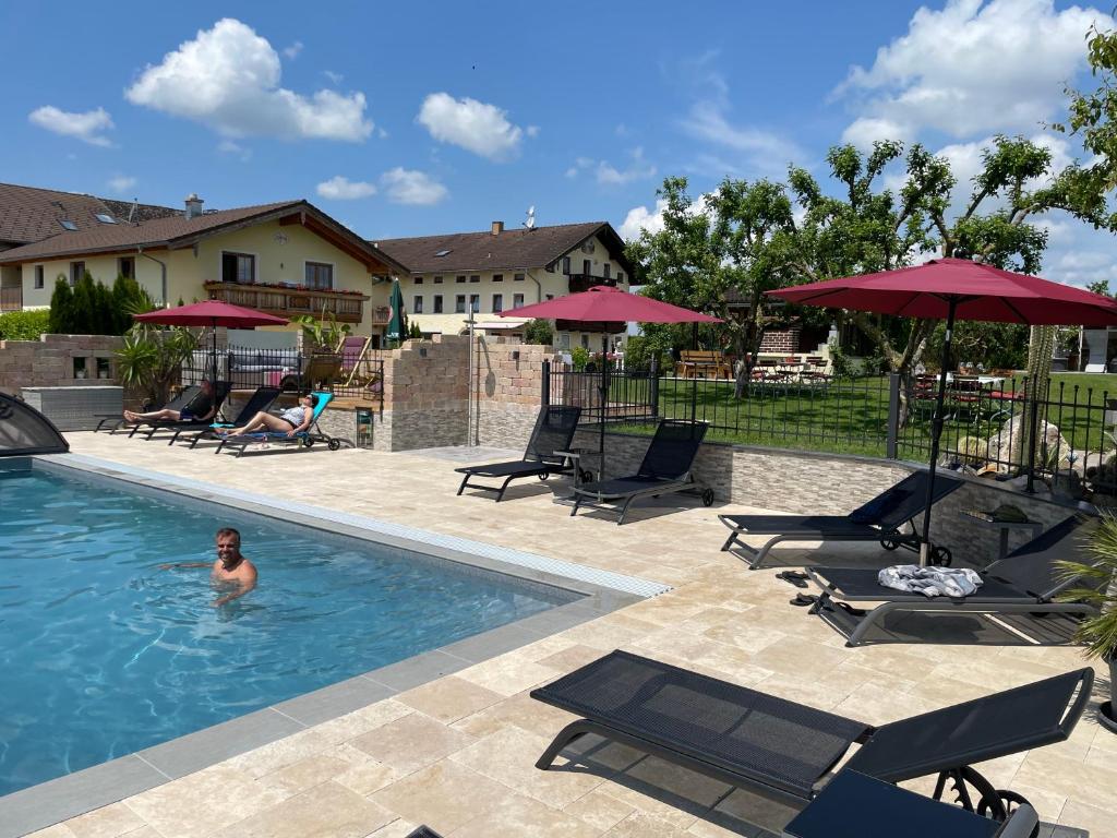 a man in a swimming pool with chairs and umbrellas at Reiherhof in Brünning