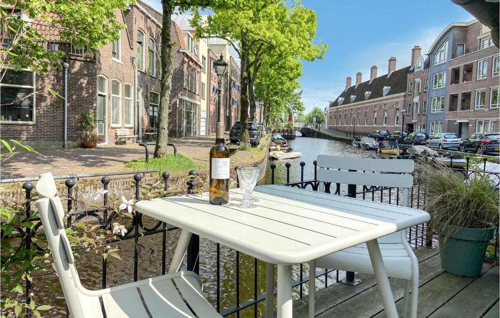 Beautiful Home In Alkmaar With Kitchen في ألكمار: طاولة بيضاء مع زجاجة من النبيذ وكرسيين
