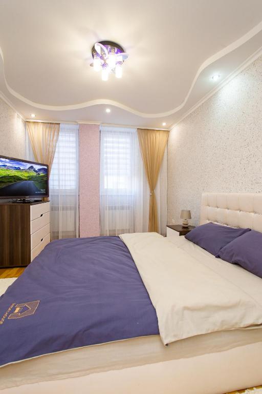 1 dormitorio con 1 cama grande y TV de pantalla plana en Центр. Хмельницького. 2 спальні, en Ternopilʼ