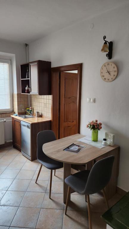 une cuisine avec une table, des chaises et une horloge murale dans l'établissement Apartmán č1 Bojnice 450m od centra, à Bojnice