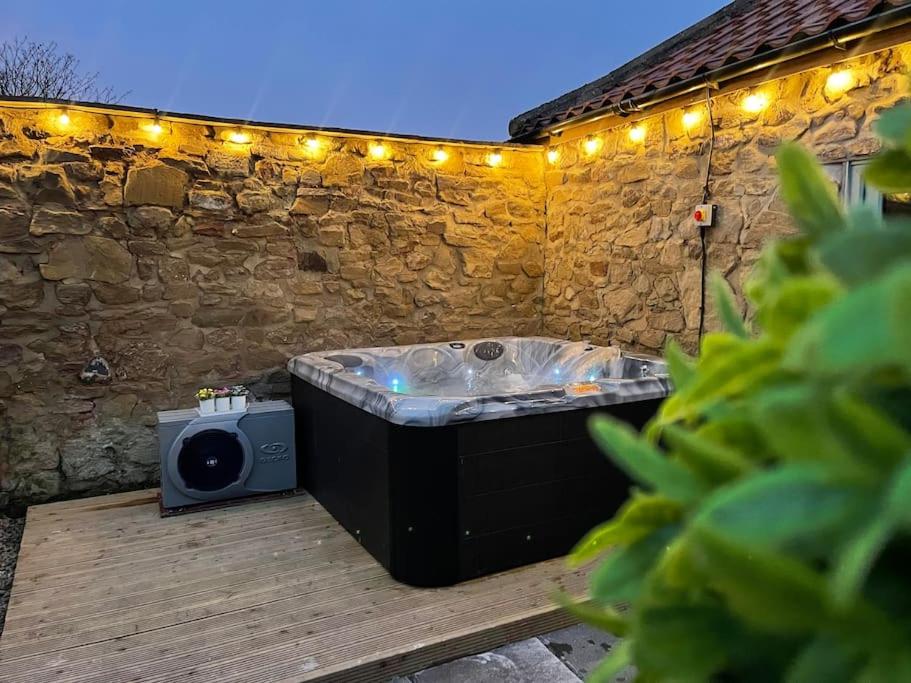 The Old Moat Barn - With Private Hot Tub في ستوكتون-أون-تيز: حوض استحمام ساخن على سطح خشبي مع أضواء