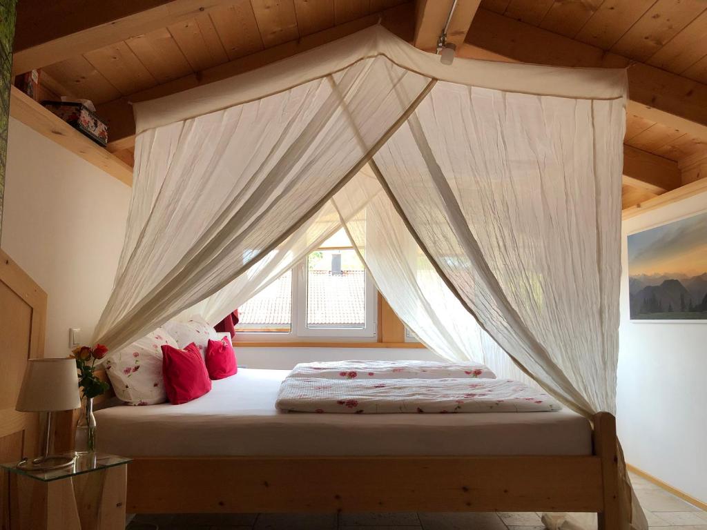 a bedroom with a canopy bed with white curtains at s‘Fleckerl in Lenggries