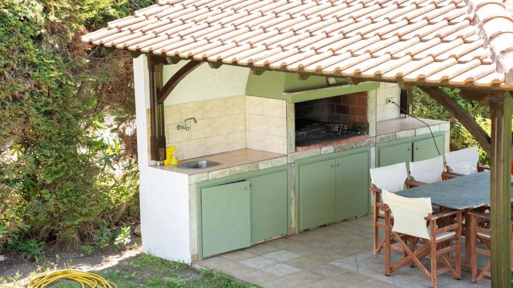 an outdoor kitchen with a table and a roof at Alexandros Hotel Apartments in Vourvourou