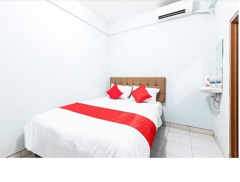 uma cama com almofadas vermelhas num quarto branco em Hotel Cemara Gading em Bubulak 3
