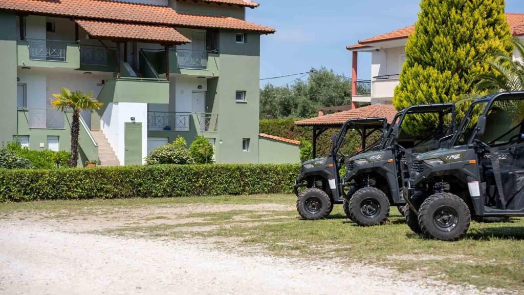 two utility vehicles parked in front of a building at Alexandros Hotel Apartments in Vourvourou