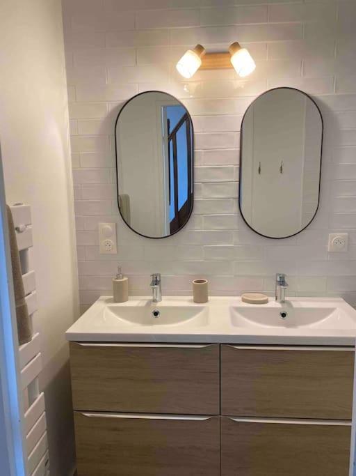 a bathroom with two sinks and two mirrors at La maison du Mineroy in Champignelles